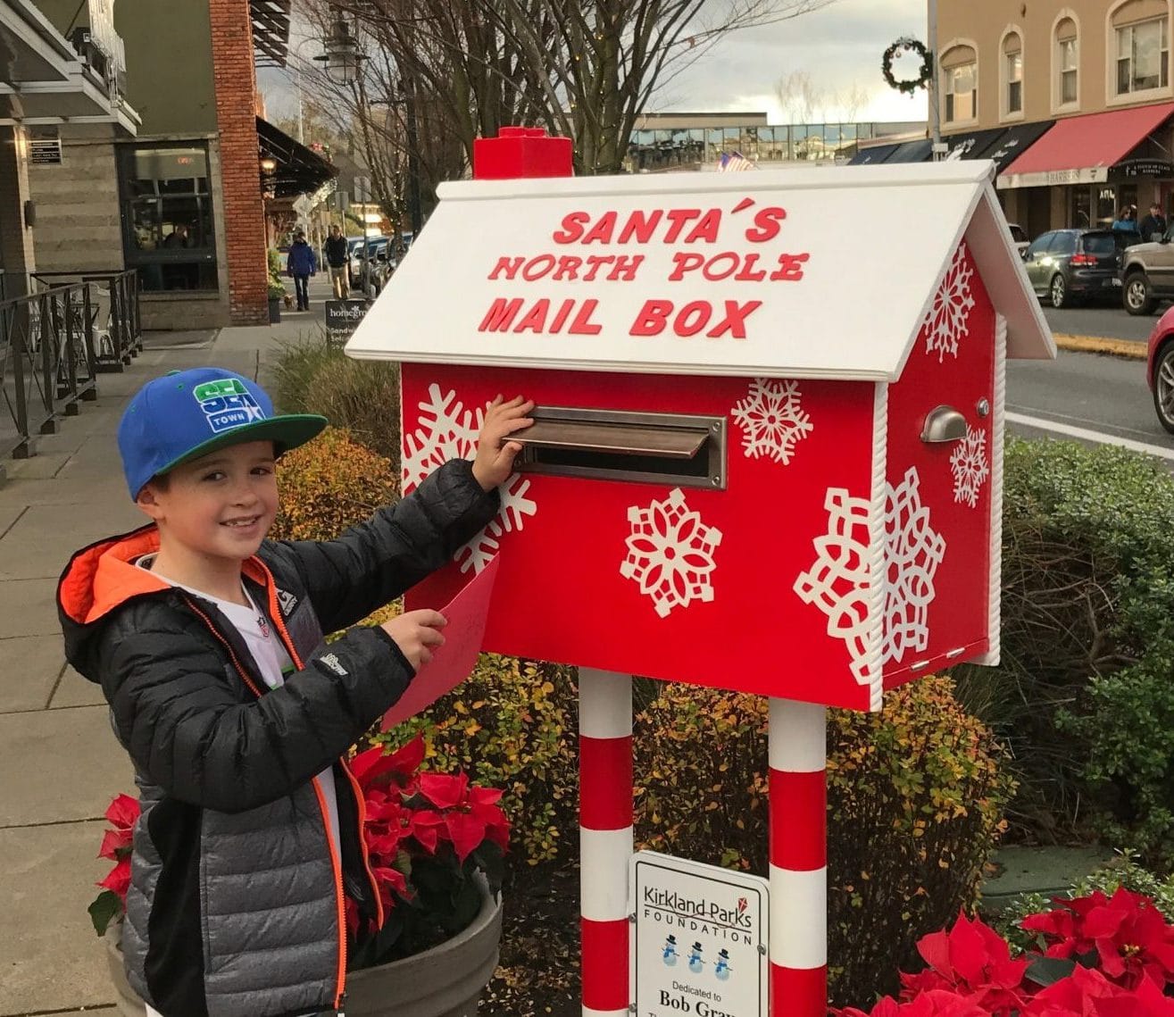 boy inserting letter in santa's mailbox